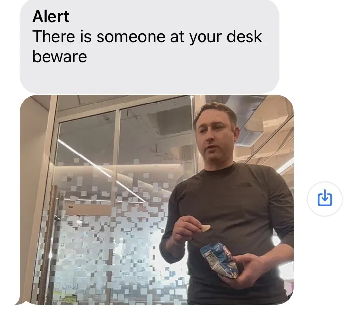 Text message reading 'Alert There is someone at your desk beware' with a photo of a person (Steve) detected by the camera as he approaches the desk.